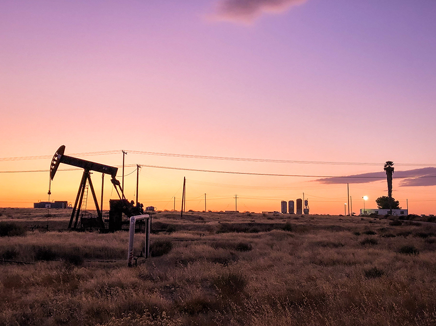 An oil rig and equipment in a field at dusk