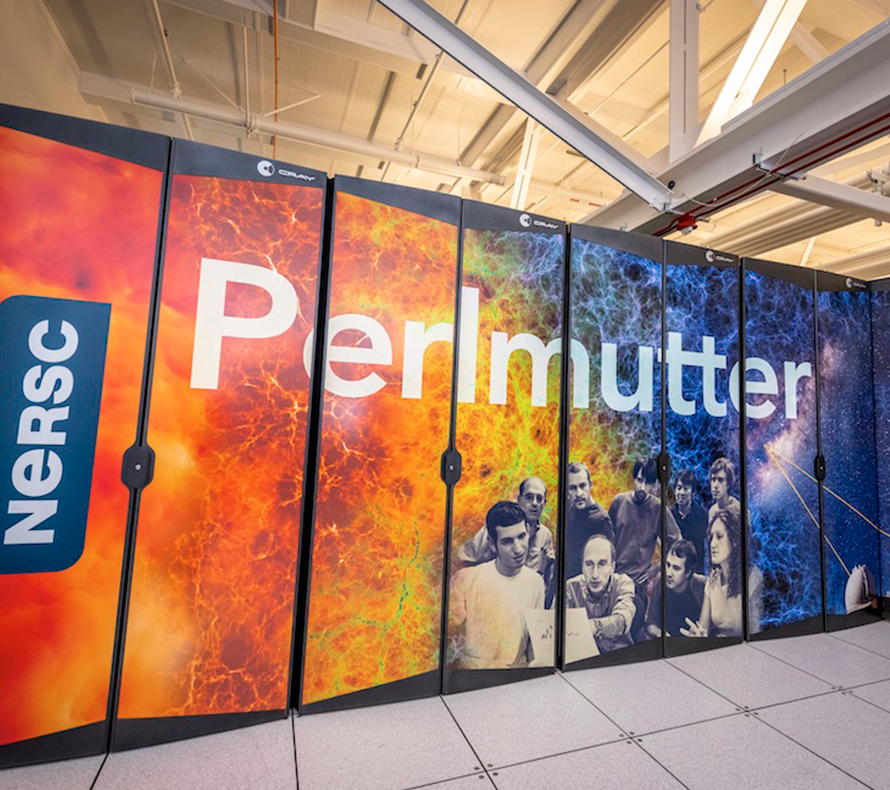 A wide shot of a large supercomputer roughly 20 feet long and cased in colorful plastic that reads “Perlmutter.” A man is holding open one of the cases on the end and peering inside