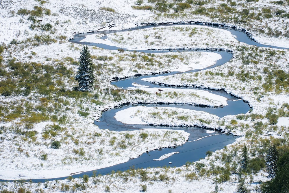 river winds through snow-covered slope